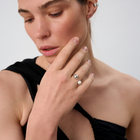 Woman wearing open-band silver ring featuring asymmetrical ends with silver sphere and freshwater pearl. 