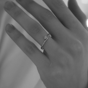 Woman's hand wearing a 14k white gold ring featuring a pear-shaped diamond centered on the top, with a white background.