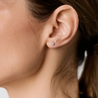 Woman wearing white gold stud earrings set with round brilliant-cut diamonds.