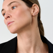 Woman wearing white gold stud earrings set with round brilliant-cut diamonds.