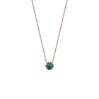 Yellow gold pendant featuring a round emerald, suspended from a delicate gold chain. 