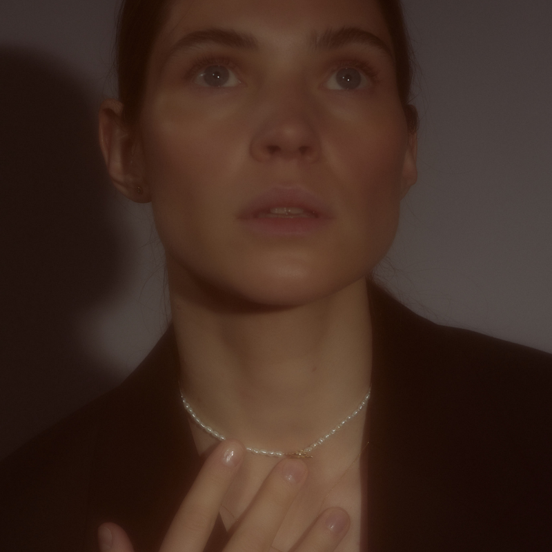Woman wearing a delicate freshwater pearl necklace featuring organically shaped pearls and a minimalist yellow gold clasp.