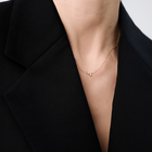 Woman wearing a minimalist necklace featuring two pear-cut diamonds set on a fine 14k yellow gold chain.