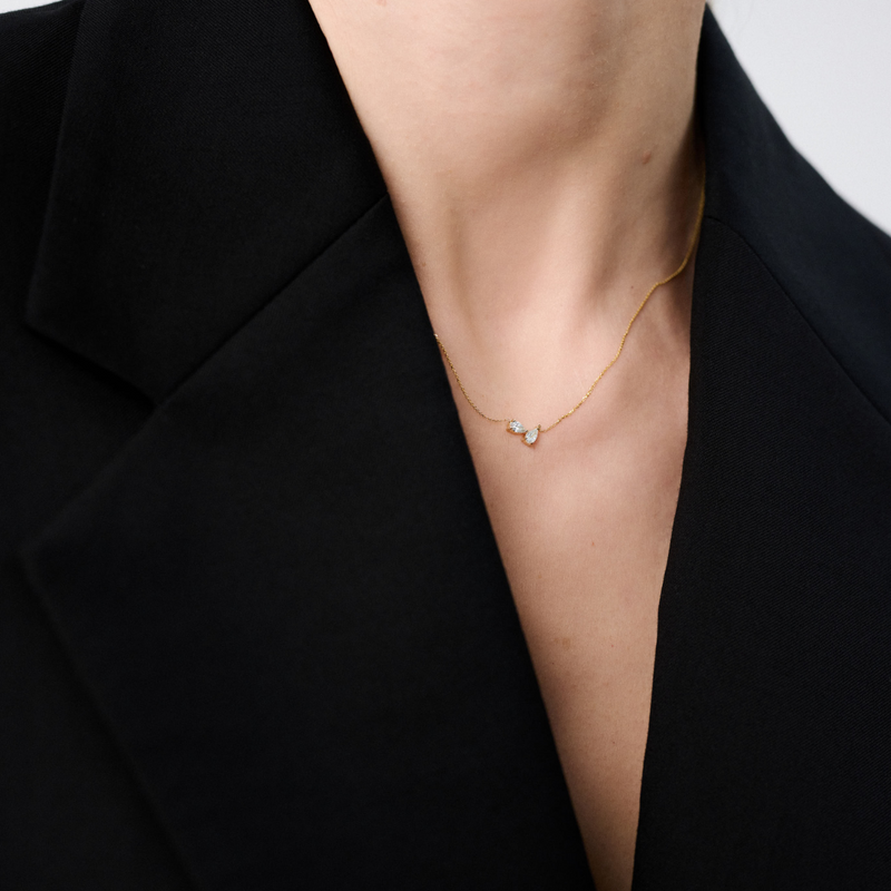Woman wearing a minimalist necklace featuring two pear-cut diamonds set on a fine 14k yellow gold chain.