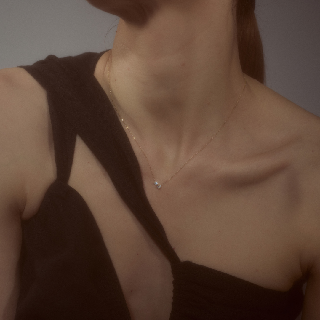 Woman wearing a minimalist necklace featuring two pear-cut diamonds set on a fine 14k yellow gold chain.