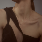 Woman wearing a minimalist necklace featuring two pear-cut diamonds set on a fine 14k yellow gold chain.