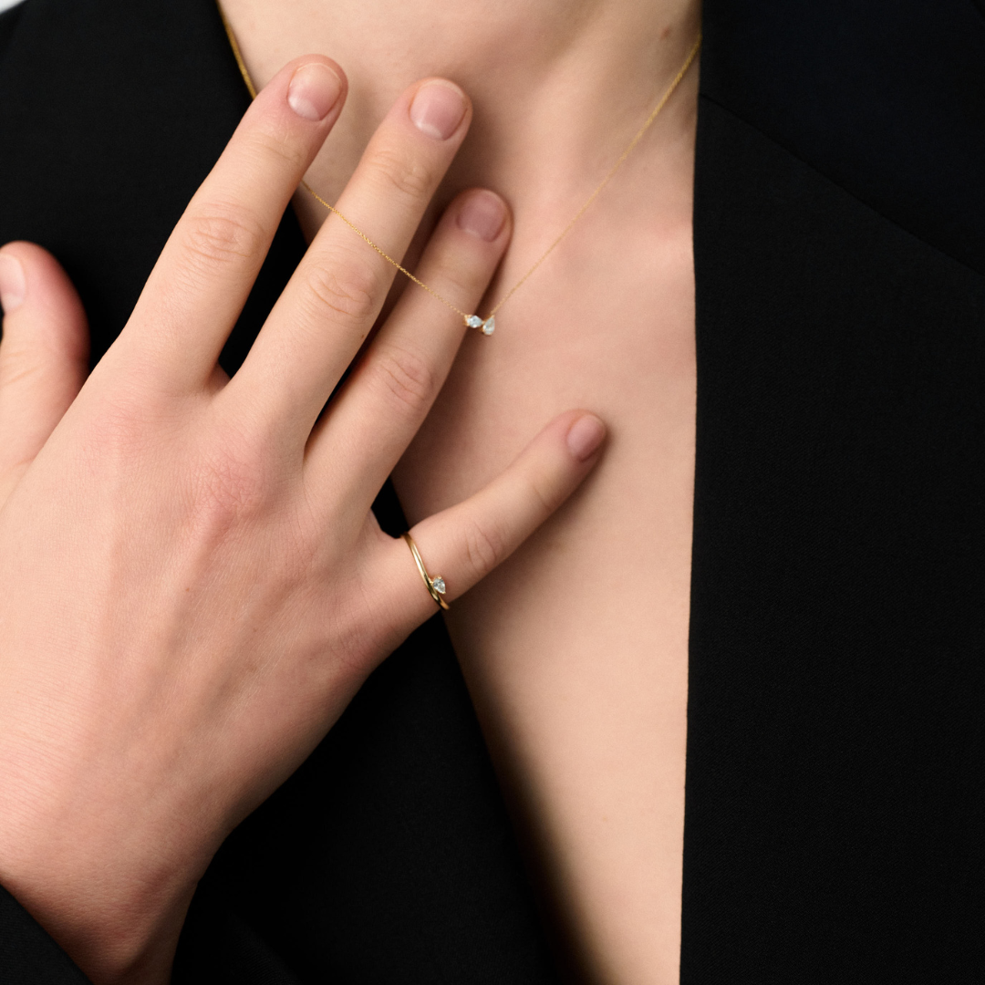 Woman wearing a 14k yellow gold ring with a pear-shaped diamond centerpiece.