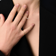 Woman wearing a 14k yellow gold ring with a pear-shaped diamond centerpiece.