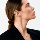 Woman wearing yellow gold stud earrings set with round brilliant-cut diamonds.