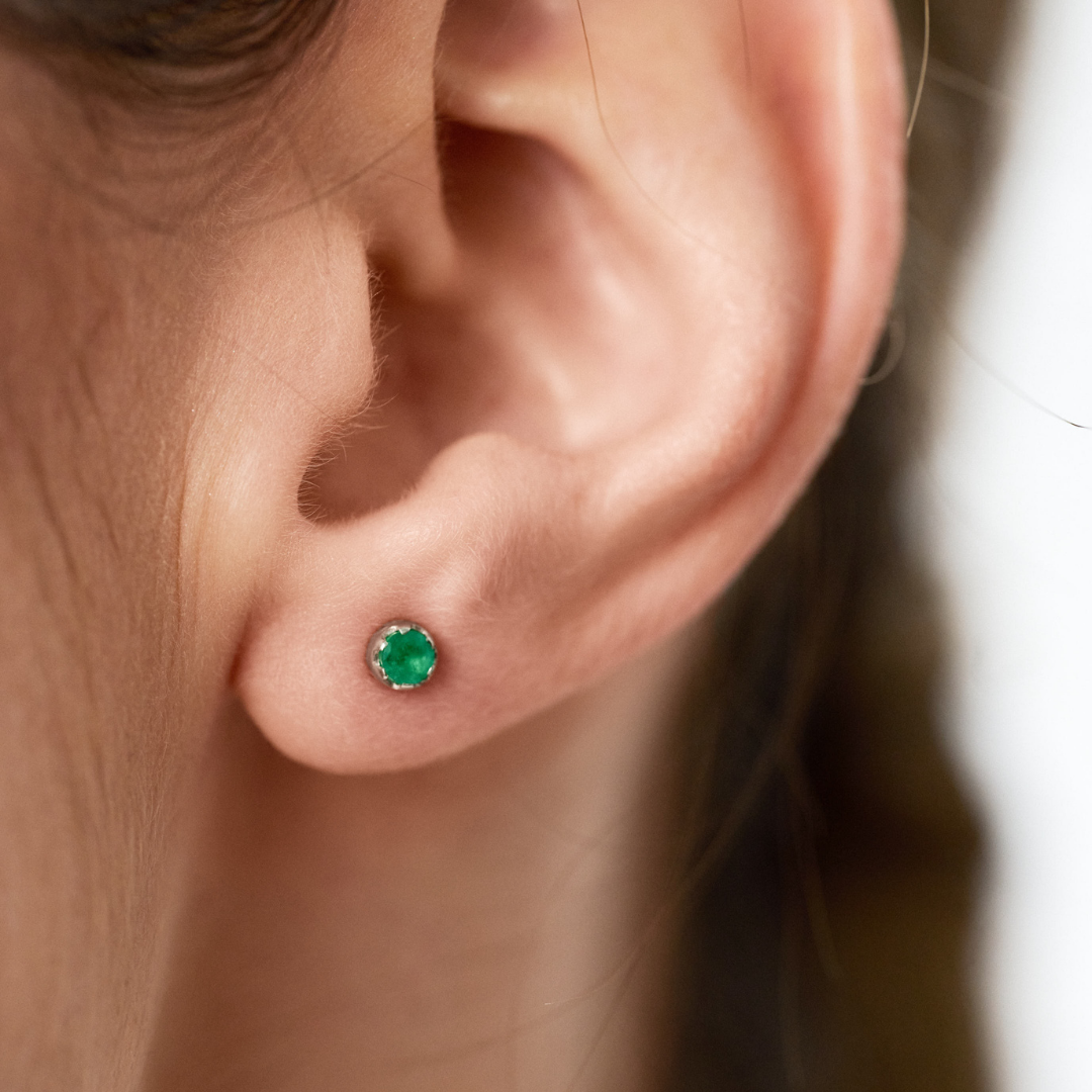 Stud earrings featuring round emeralds set in 14k yellow gold.