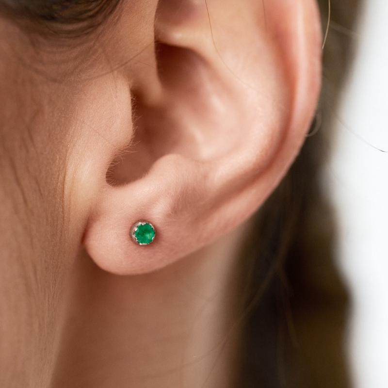 Stud earrings featuring round emeralds set in 14k yellow gold.