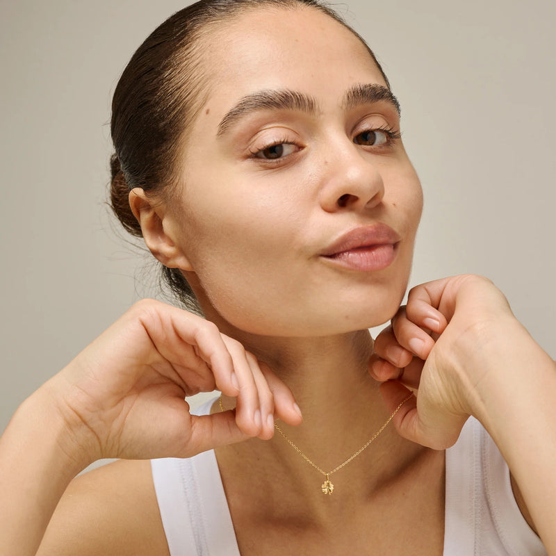 Woman wearing a gold necklace against a neutral background