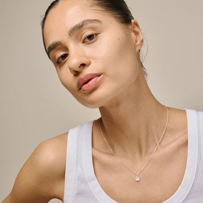 Woman wearing a delicate necklace against a neutral background
