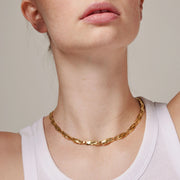 Gold necklace worn by a person with a neutral background