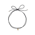 Black choker necklace with a gold charm on a white background