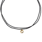 Black cord necklace with a gold pendant on a white background