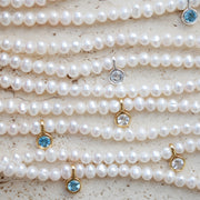 Pearl necklaces with topaz gemstone pendants on a textured surface