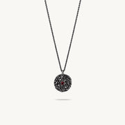 Oxidised silver chain necklace featuring a round, textured disc pendant with a small red sapphire set in the center