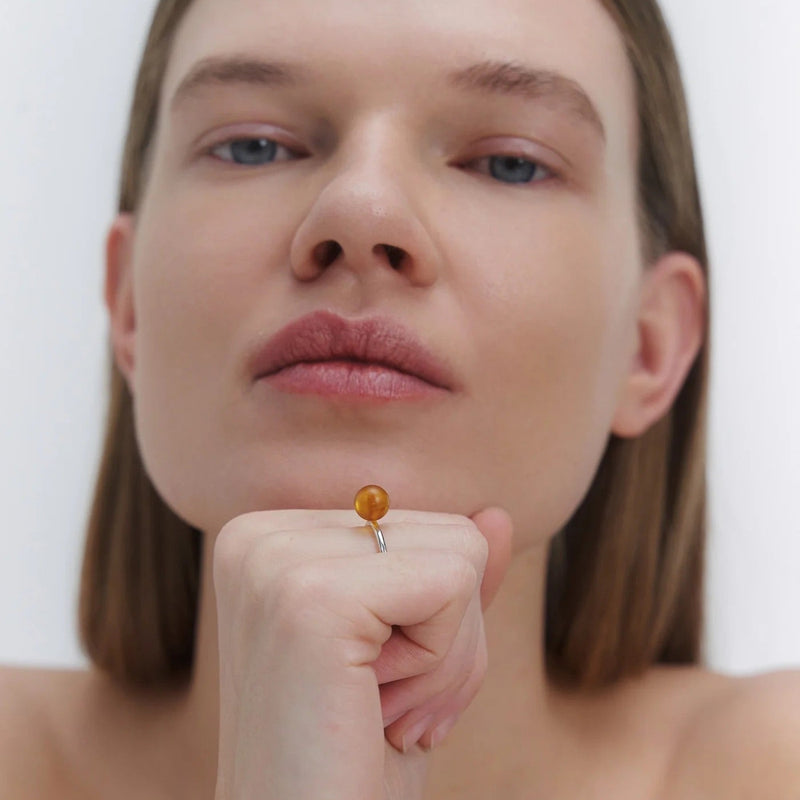 A sleek silver ring featuring a medium size natural Baltic amber stone.