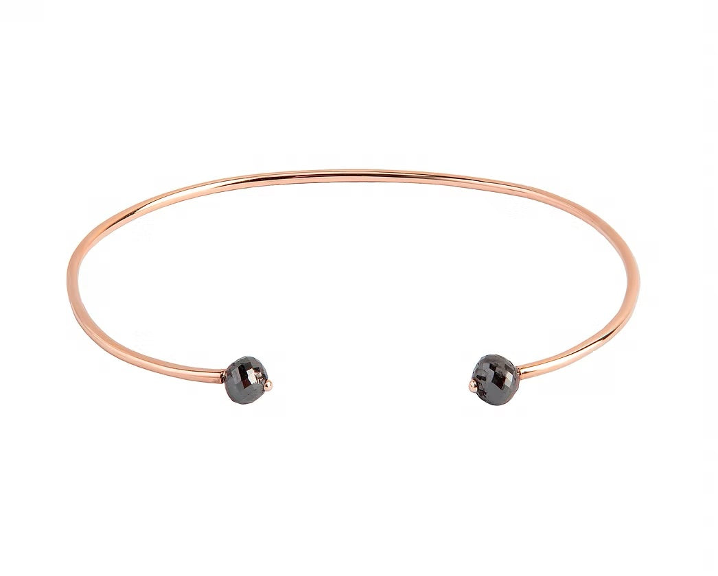 A thin rose gold open cuff bangle bracelet with two small faceted grey diamonds at the ends, shown on a plain white background.