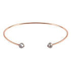 A thin rose gold open cuff bangle bracelet with two small faceted grey diamonds at the ends, shown on a plain white background.