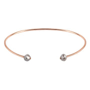 A thin rose gold open cuff bangle bracelet with two small faceted grey diamonds at the ends, shown on a plain white background.