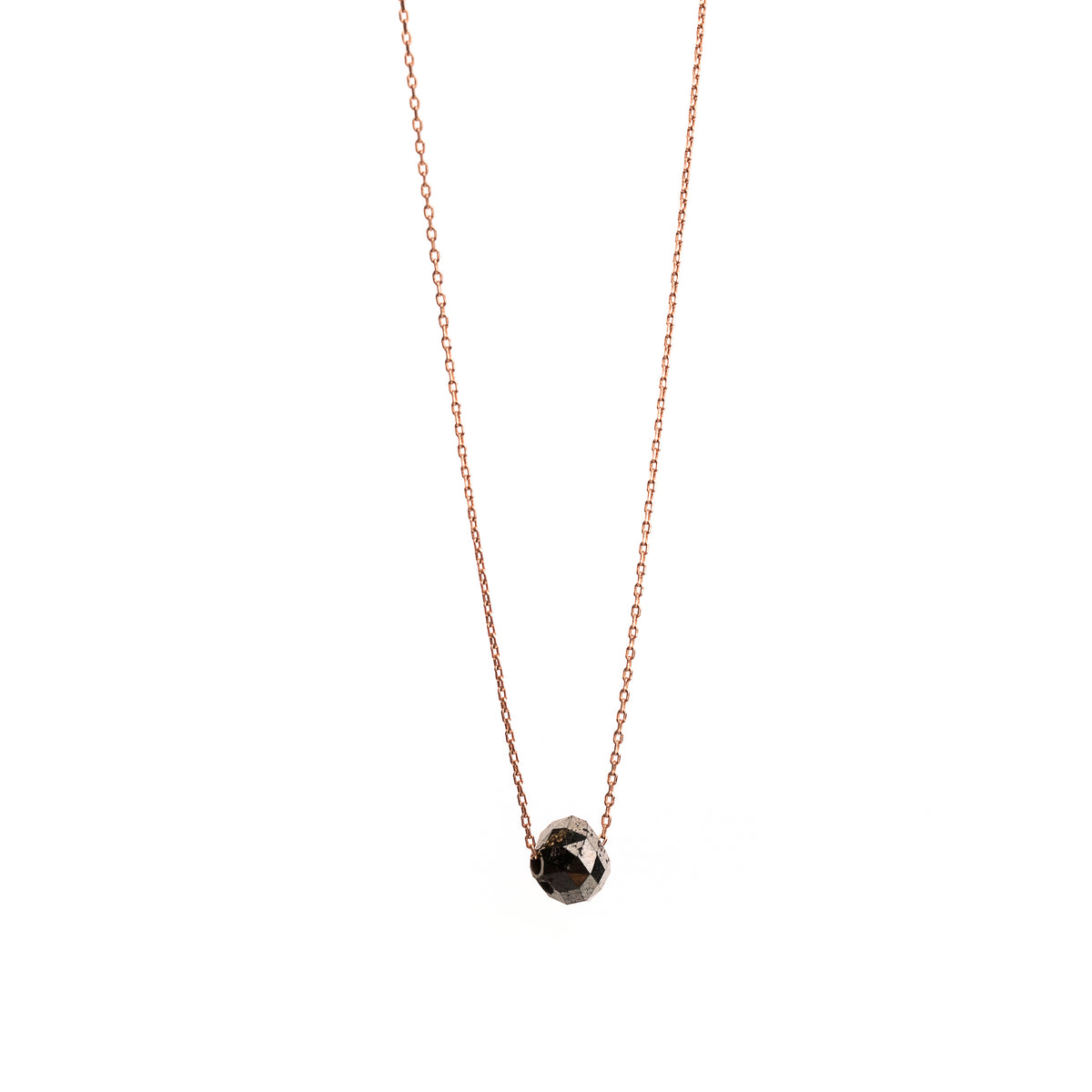 A delicate rose gold chain necklace with a small, faceted black gemstone pendant, shown against a plain white background.