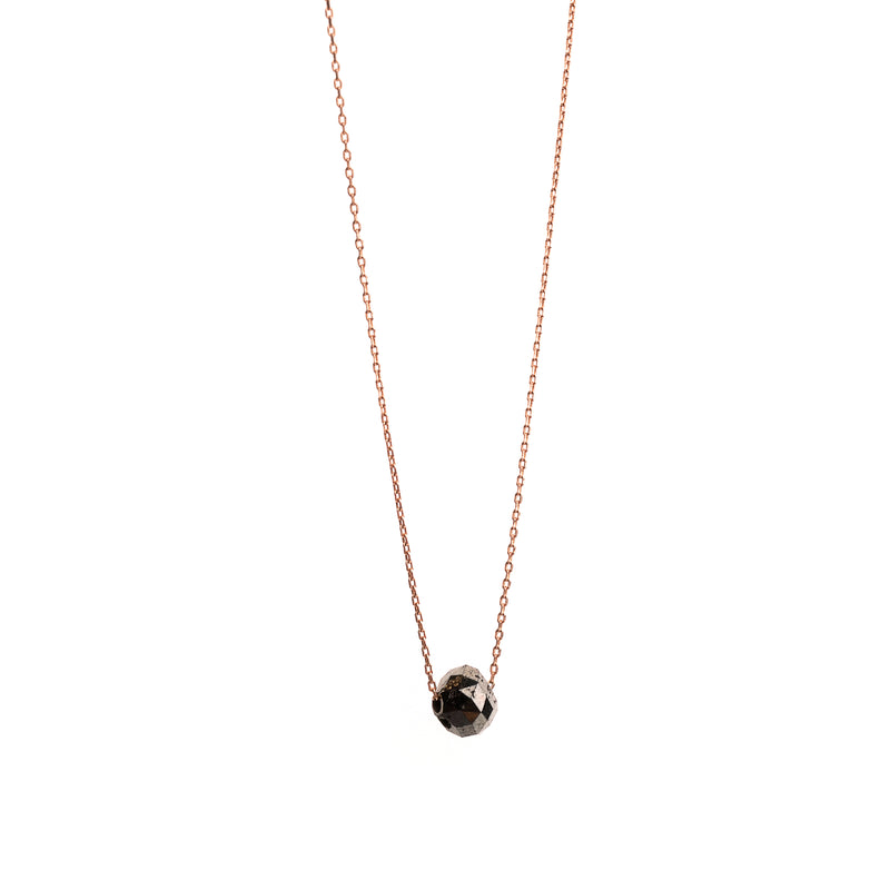 A delicate rose gold chain necklace with a small, faceted black gemstone pendant, shown against a plain white background.