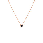 A delicate rose gold chain necklace with a small bezel-set ocean blue diamond pendant, shown against a plain white background.