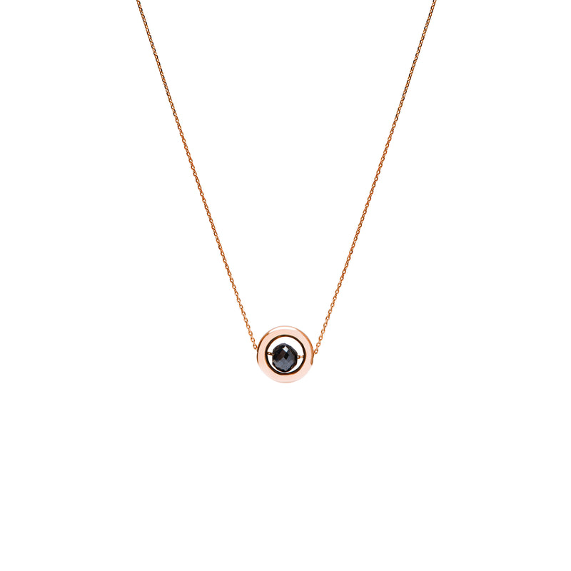 A delicate rose gold chain necklace featuring a small circular pendant with a gold outer ring and a dark, nearly black, faceted diamond, shown against a plain white background.