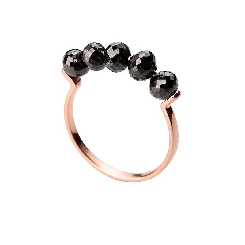 A rose gold ring featuring five faceted black diamonds beads set across the top, photographed on a clean white background.