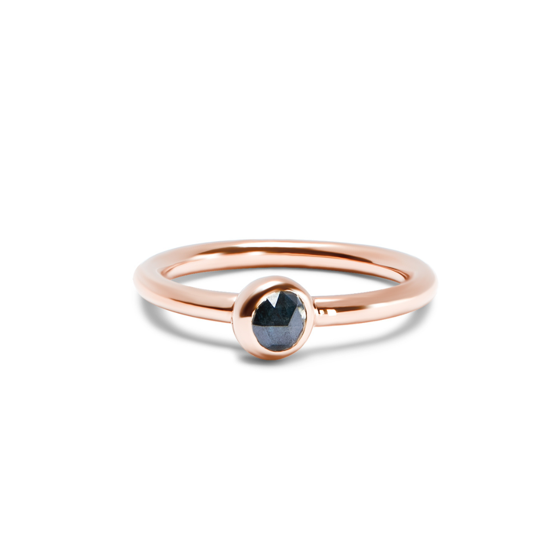 A rose gold ring with a single faceted dark ocean blue gemstone in a bezel setting, shown on a clean white background.
