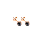 A pair of rose stud earrings with round black diamonds centers, shown on a plain white background.