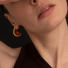 Close-up of a model wearing a gold crescent-shaped hoop earring with a round amber stone.