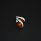 A pair of silver  twisted rope-style earrings with smooth round amber stone, photographed on a dark black background.