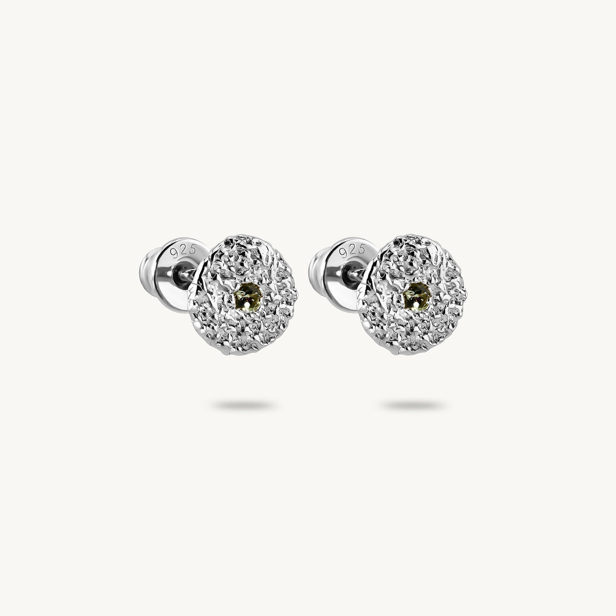 A pair of silver stud earrings with circular disc motifs, a central halo of green sapphires, on a clean white background.