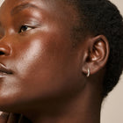 Close-up of a woman's face with a neutral expression, wearing a small hoop earring.