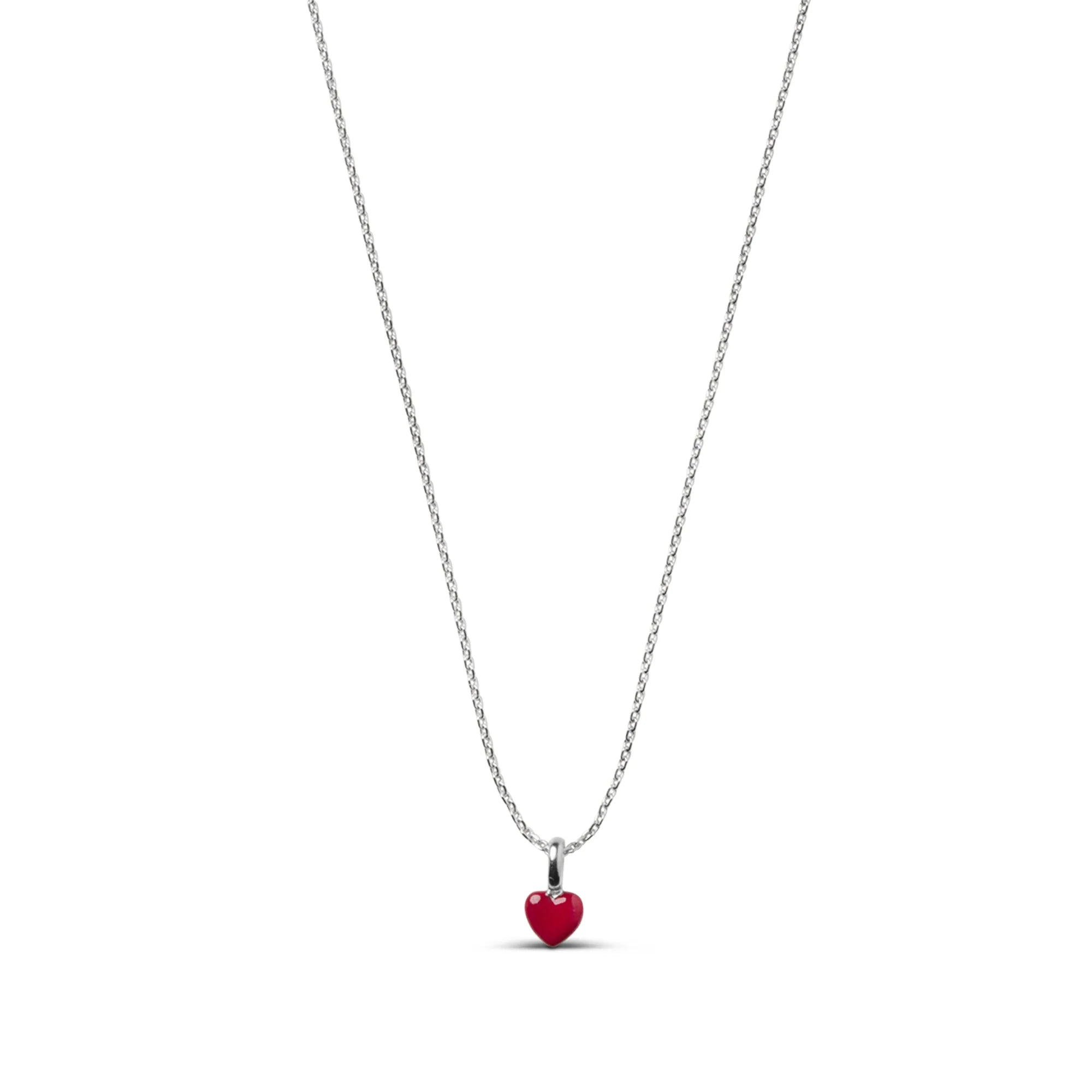 A delicate silver chain necklace featuring a small, polished red heart pendant, shown against a solid white background.
