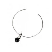 A minimalist silver necklace with a single black spherical amber hanging from the front, set against a plain white background.