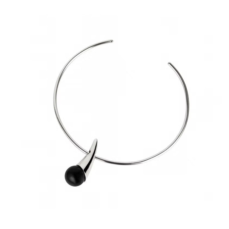 A minimalist silver necklace with a single black spherical amber hanging from the front, set against a plain white background.