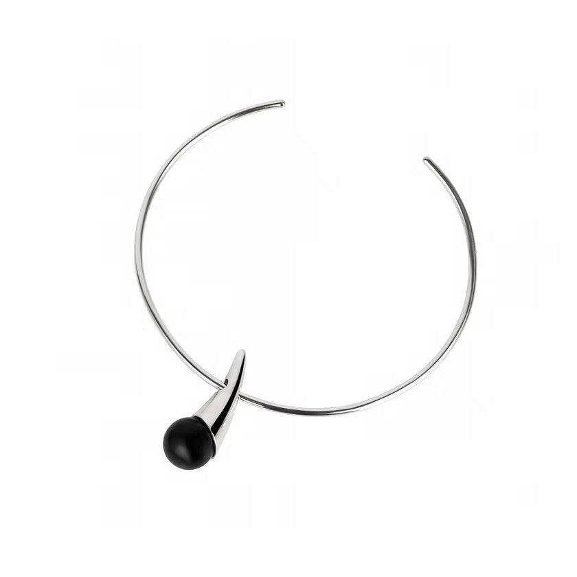 A minimalist silver necklace with a single black spherical amber hanging from the front, set against a plain white background.