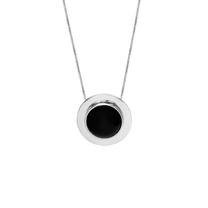 A minimalist silver pendant necklace featuring a circular silver frame with a smooth, black amber center, suspended from a delicate silver chain against a solid white background.