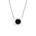 A silver square pendant necklace with a circular black amber, suspended from a silver paperclip chain against a plain white background.