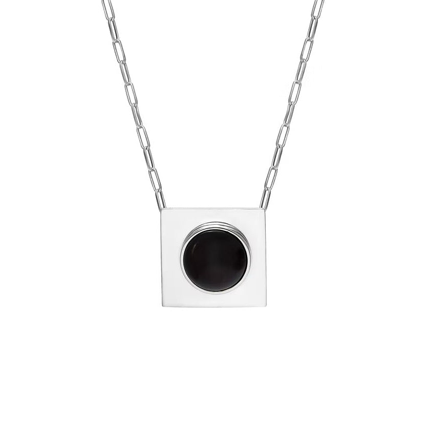 A silver square pendant necklace with a circular black amber, suspended from a silver paperclip chain against a plain white background.