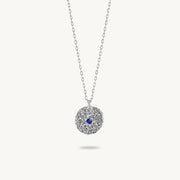 Sterling silver chain necklace featuring a round, textured disc pendant with a small blue sapphire set in the center.