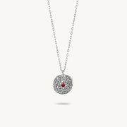 Sterling silver chain necklace featuring a round, textured disc pendant with a small red sapphire set in the center