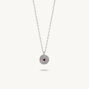 Sterling silver chain necklace featuring a round, textured disc pendant with a small red sapphire set in the center.