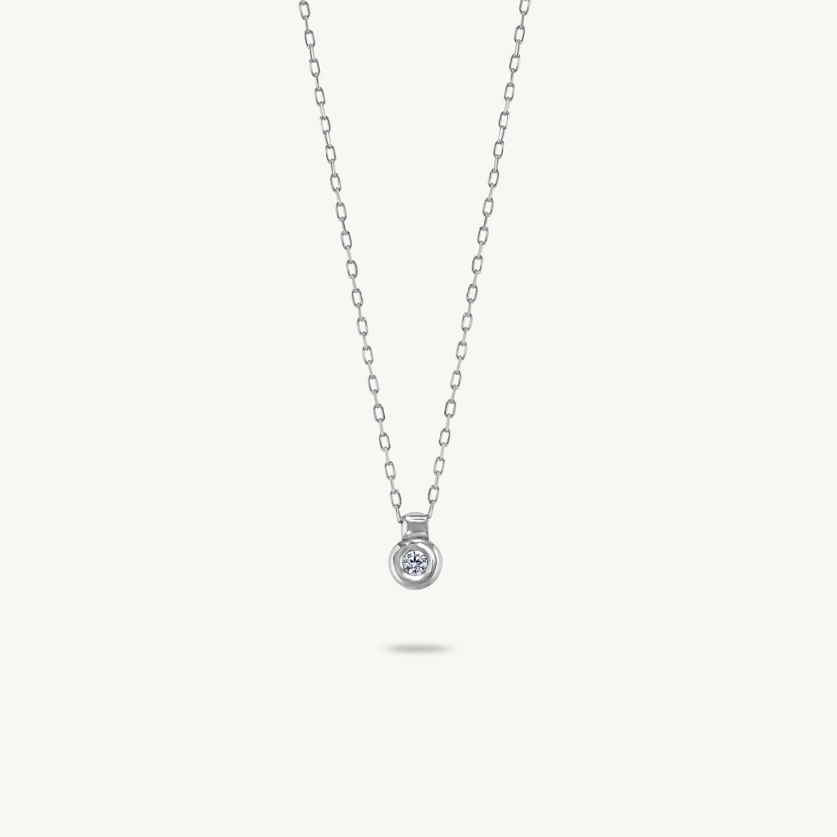 A silver pendant featuring a smooth, sculptural bezel framing a single central white sapphire.