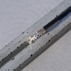 A silver ring with a textured, hammered band, resting diagonally on a speckled gray concrete surface.