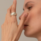 A close-up lifestyle shot of a model wearing a wide, textured silver ring on her finger, touching her nose with the other hand against a soft beige background.